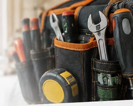 A tradesman's tool belt with spanners, screwdrivers and a tape measure